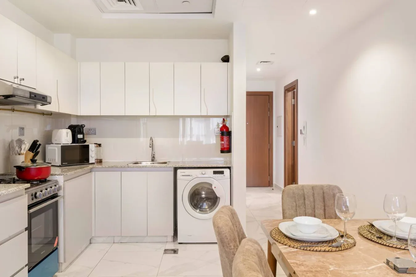 A compact kitchen opens onto a dining area with a table and chairs.