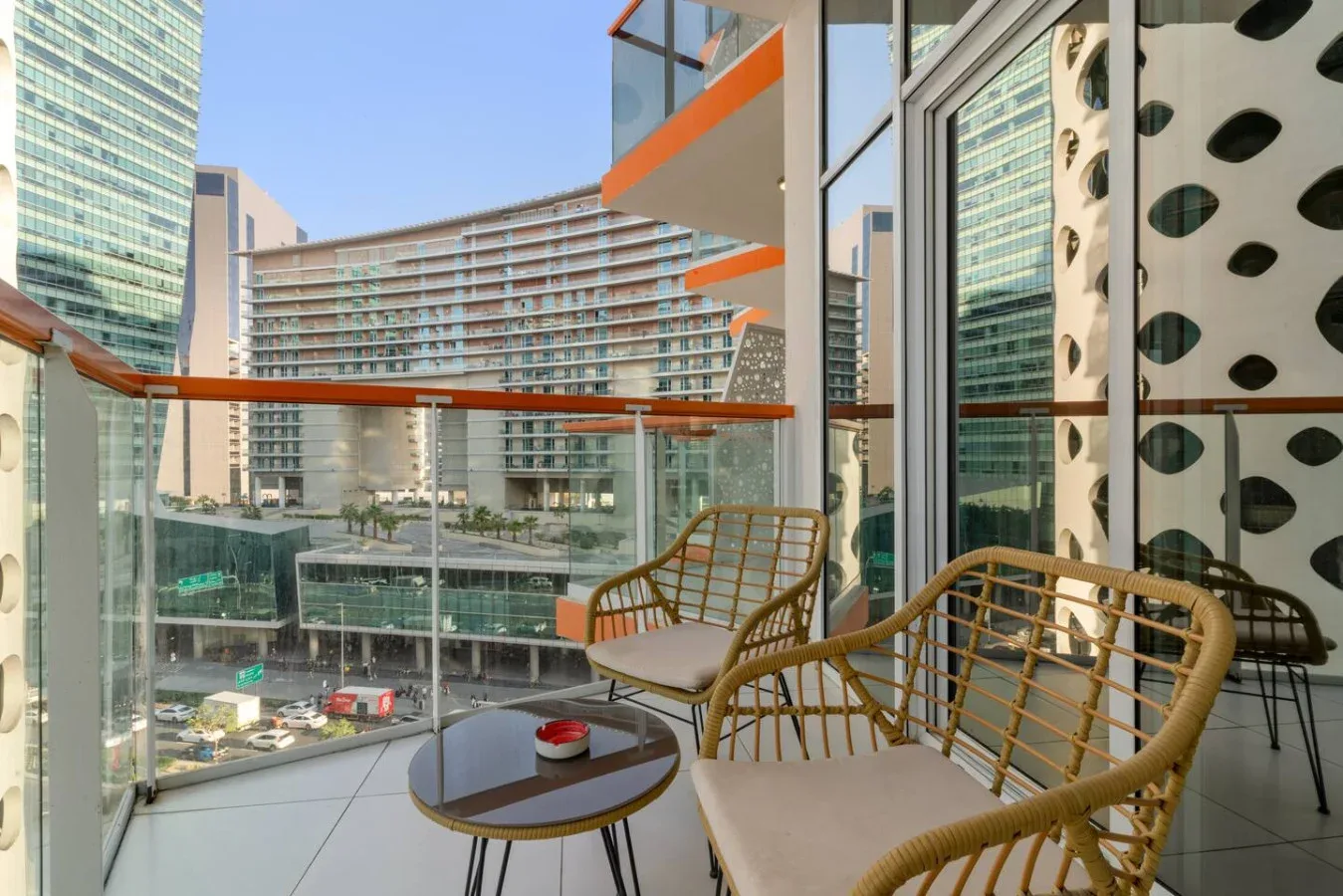 A balcony seating area overlooks nearby modern buildings.