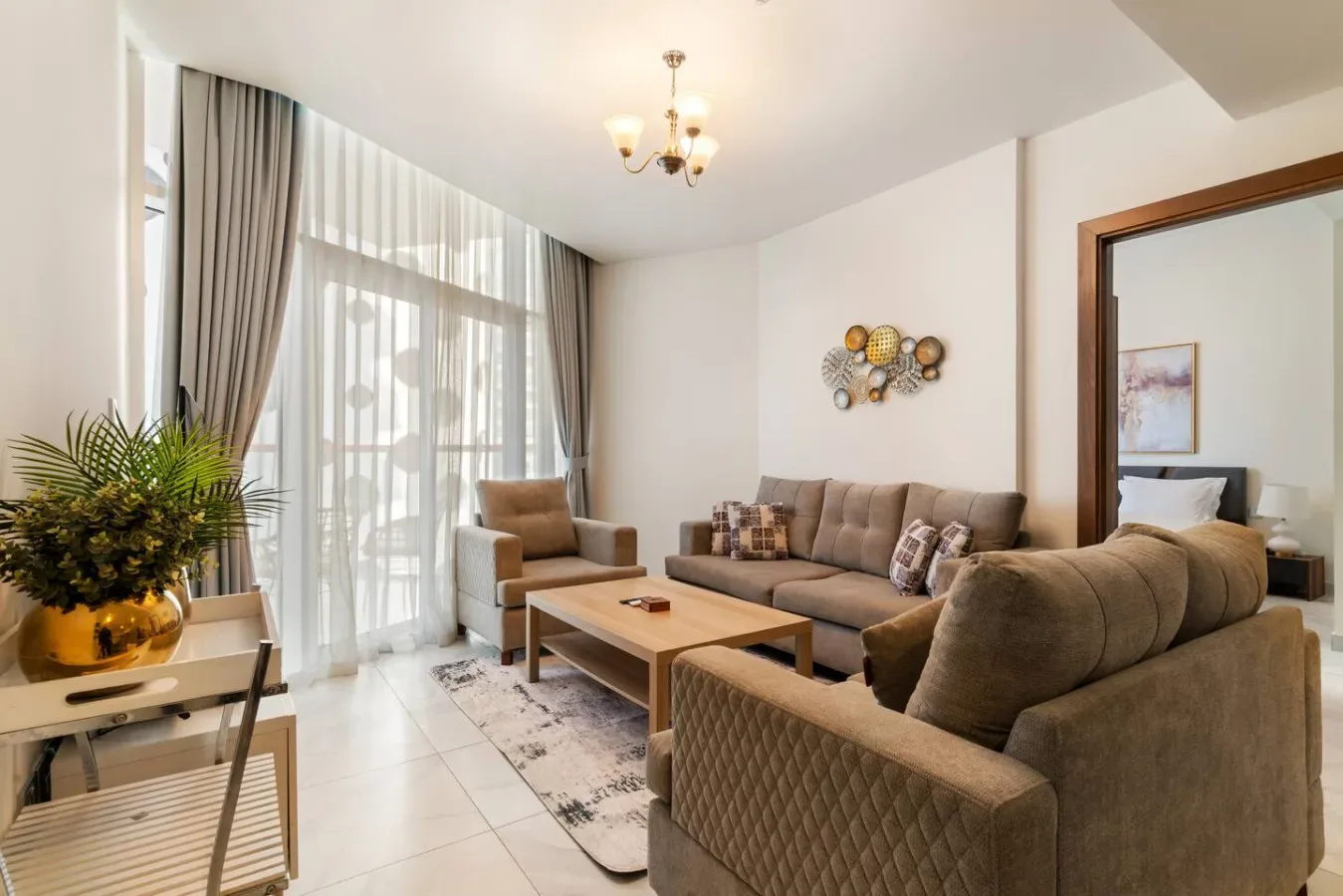 A living room with seating around a coffee table beside large curtained windows.
