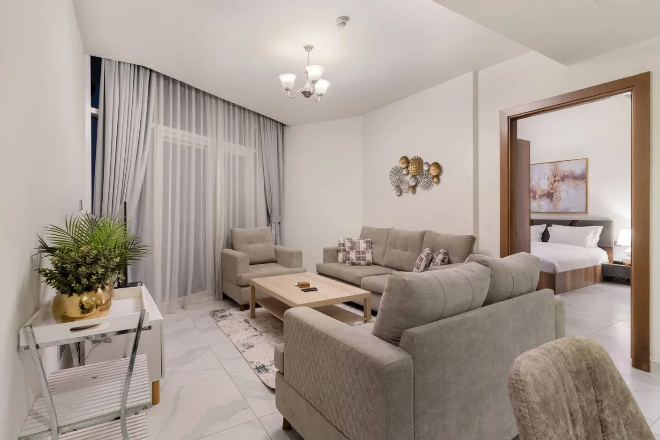 A living room with cushioned seating, a coffee table, and tall curtained windows.