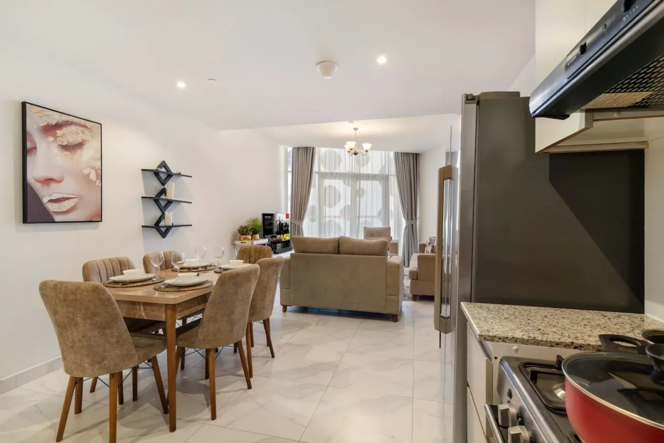 A bright open-plan living and dining area with a kitchen in the foreground.