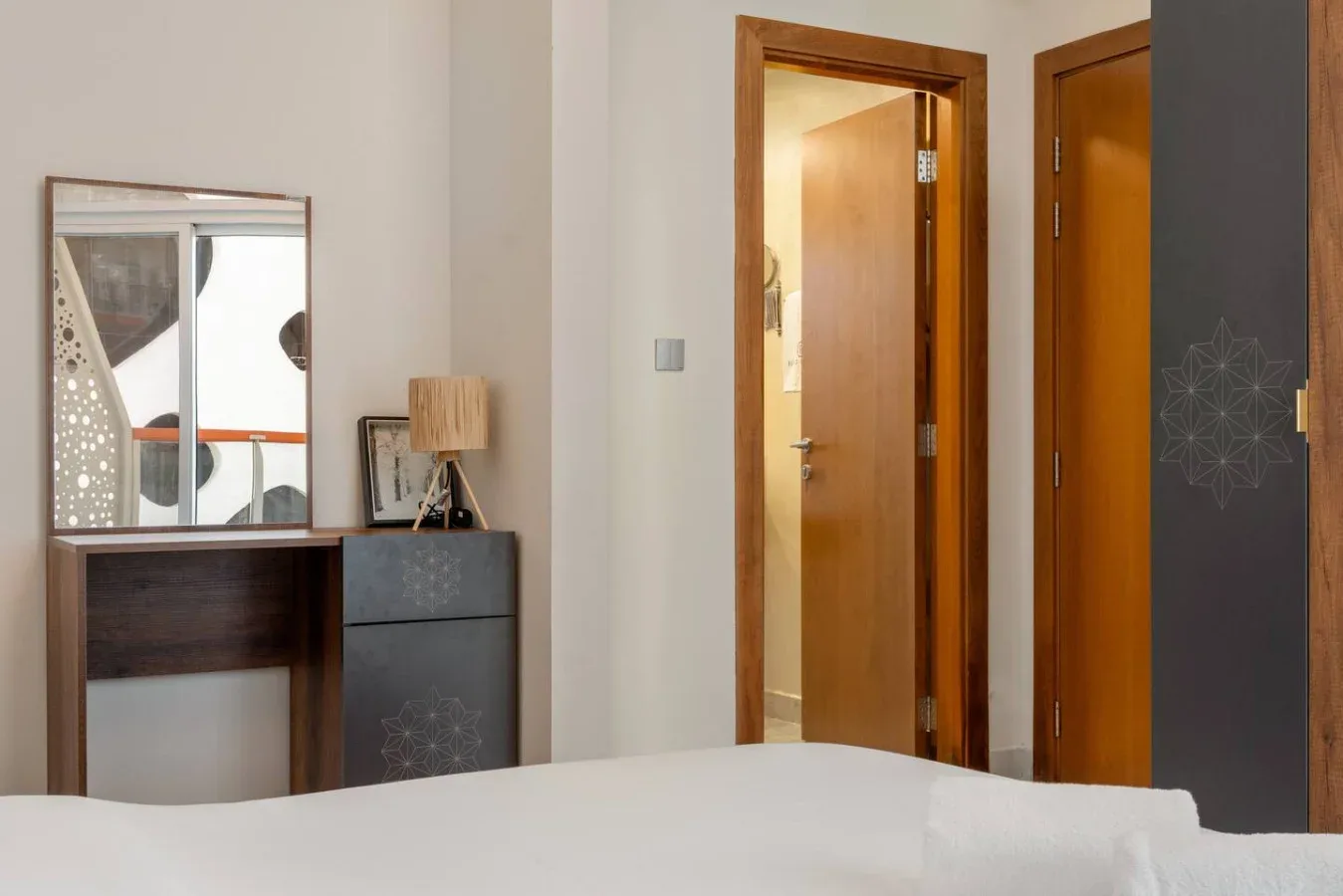 Bedroom with a dark vanity and mirror beside an open wooden door.