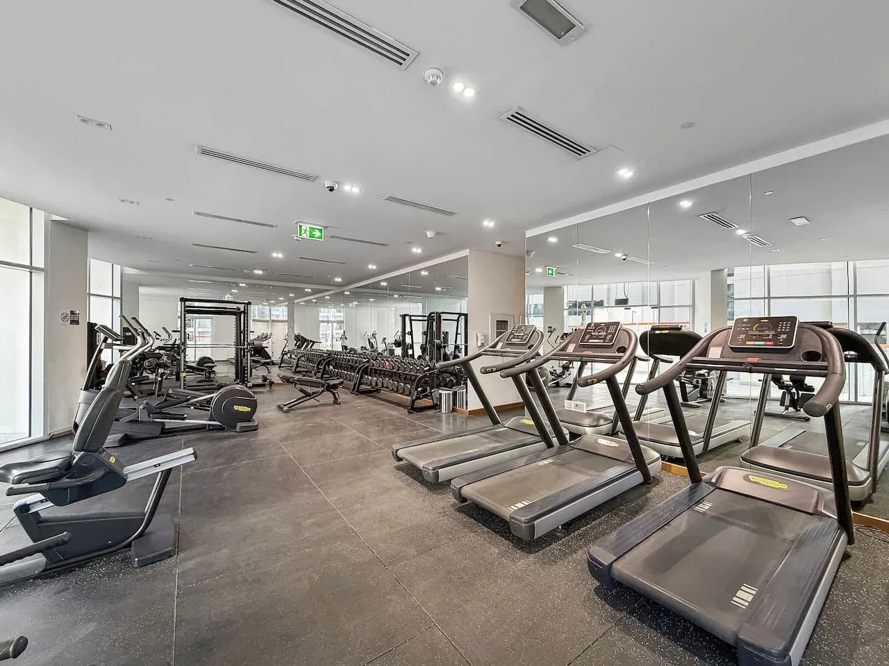 A spacious gym with rows of treadmills and other exercise equipment.