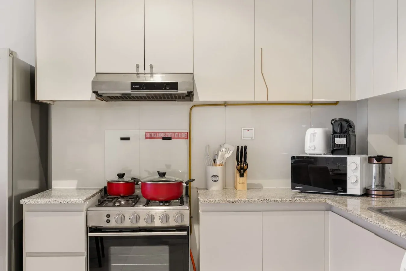 A modern kitchen with white cabinets, a stove, and countertop appliances.