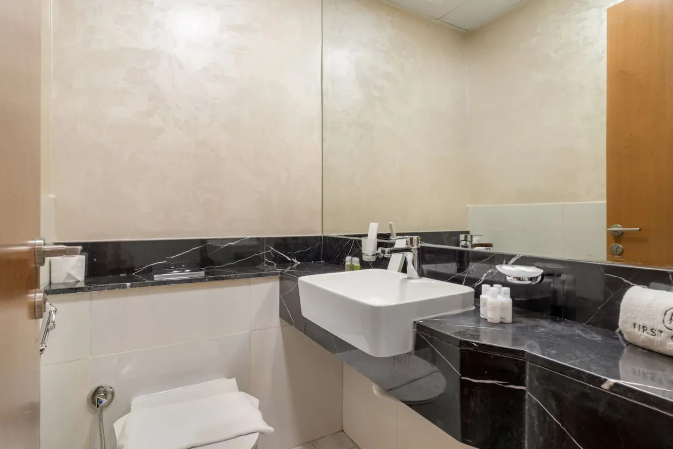 A bathroom with a white basin set into a dark countertop.