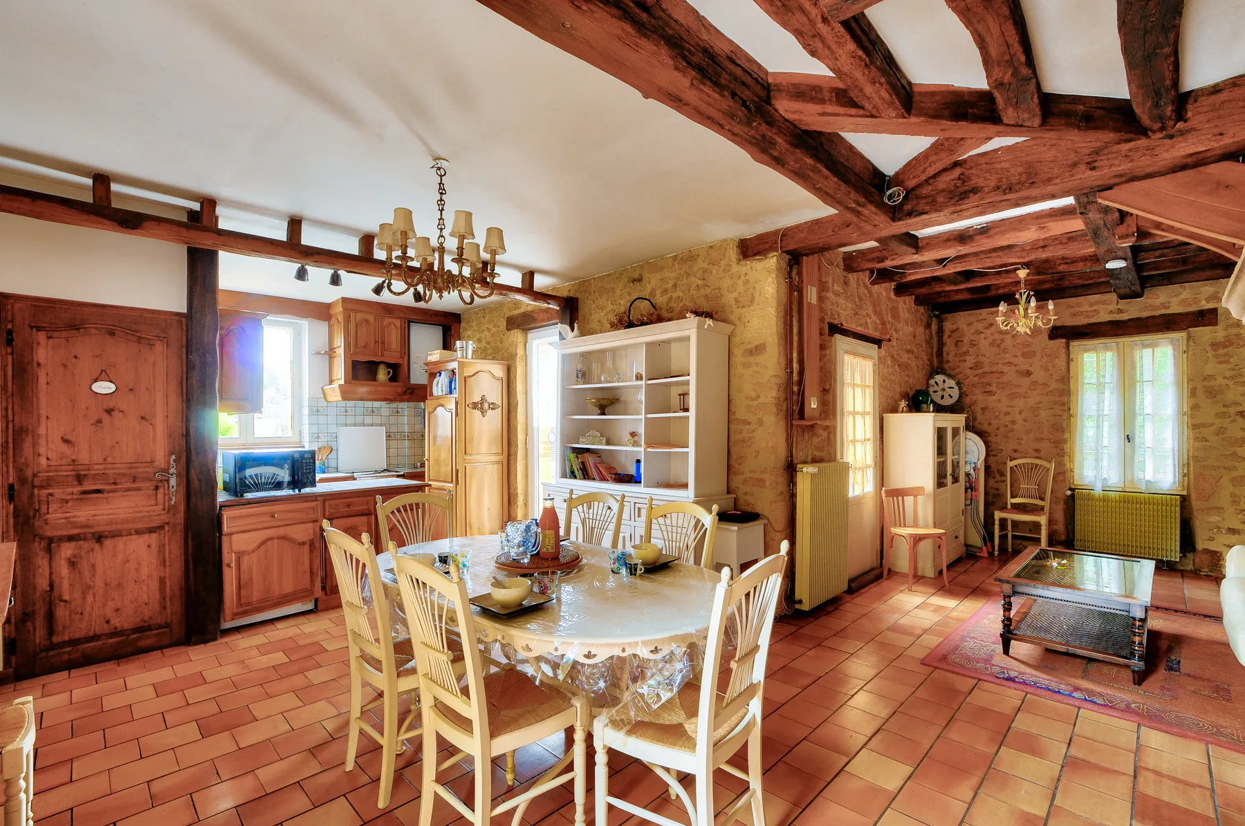 Comedor y sala rústicos con una mesa de madera y vigas expuestas.
