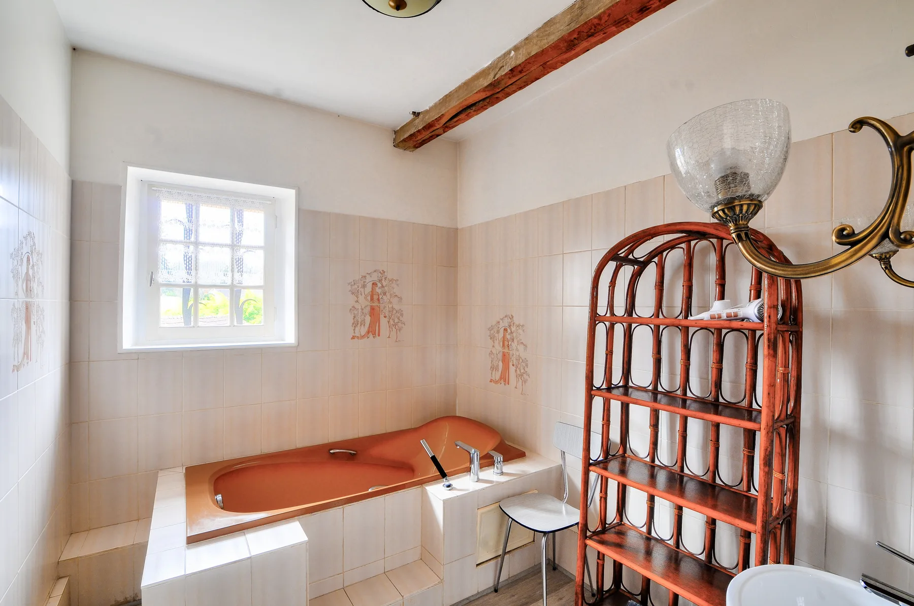 Un baño alicatado con una bañera empotrada y una estantería alta de madera.