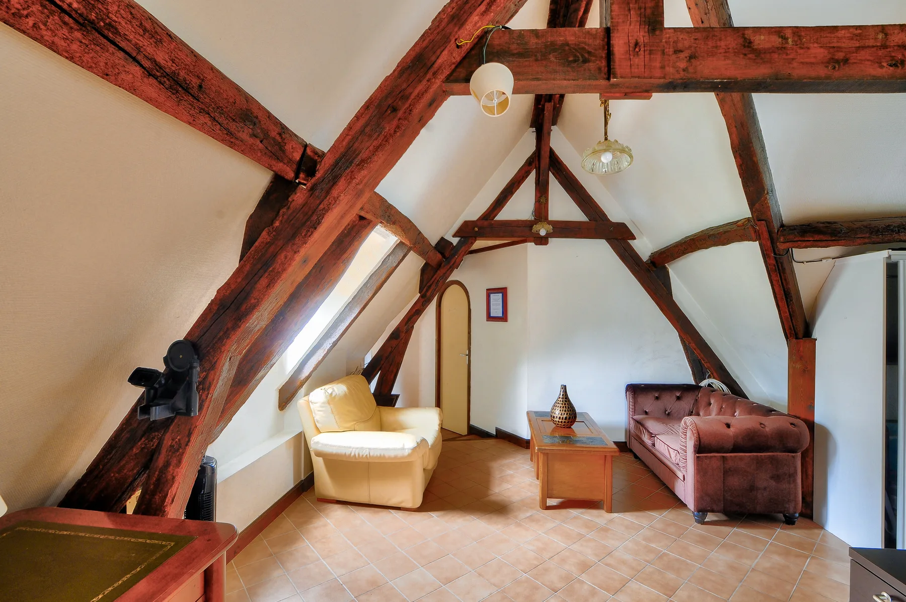 Una habitación abuhardillada amueblada, con vigas de madera y asientos.
