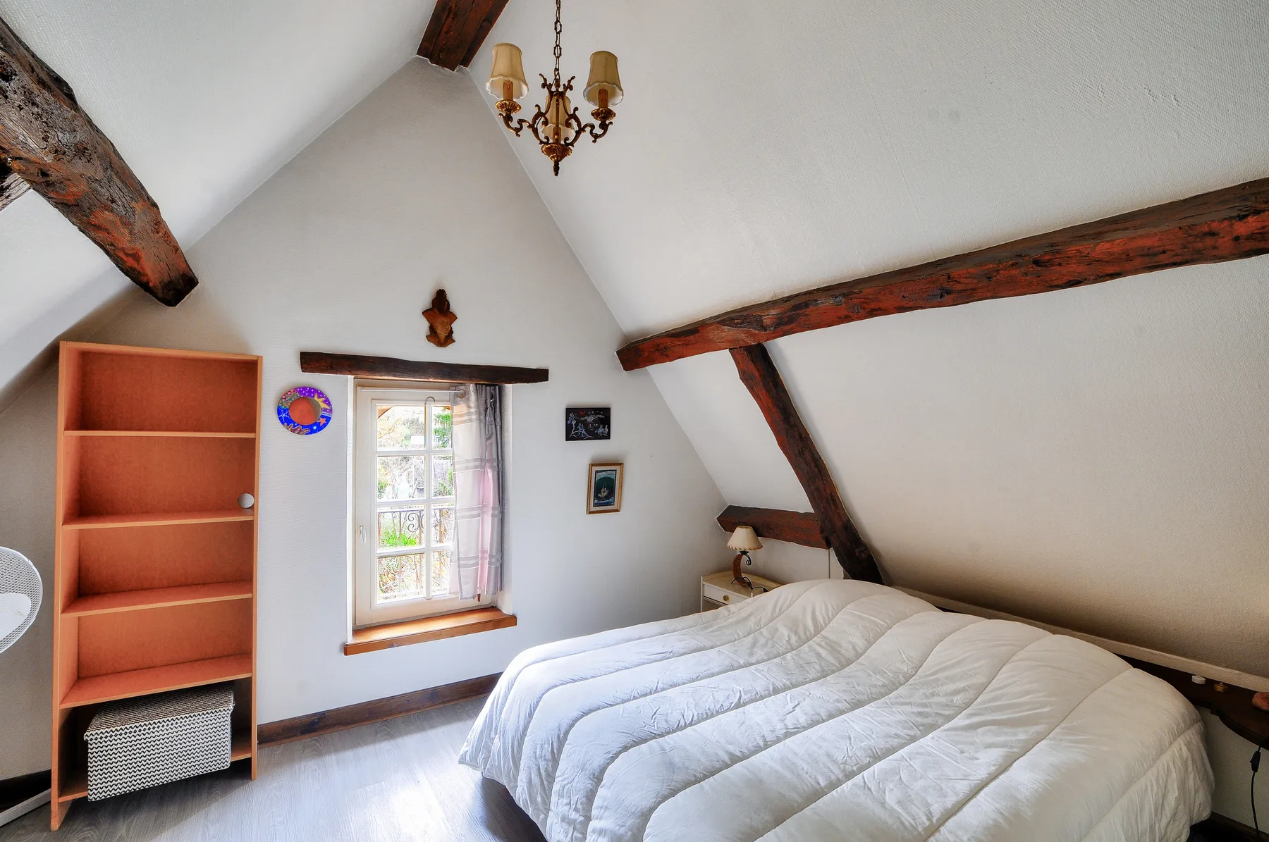 Un dormitorio con una cama grande bajo vigas de madera a la vista.