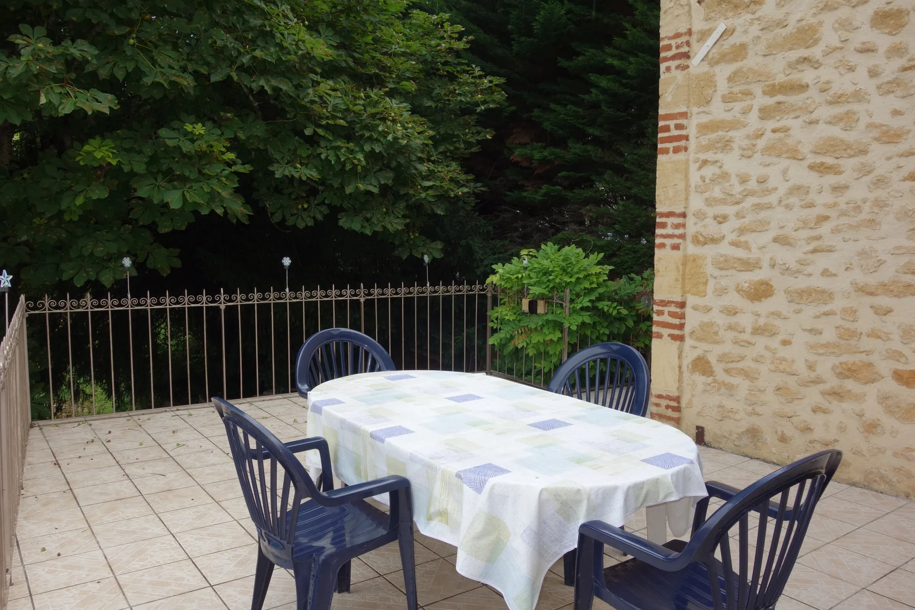 Una zona de comedor al aire libre con mesa y sillas en una terraza pavimentada.