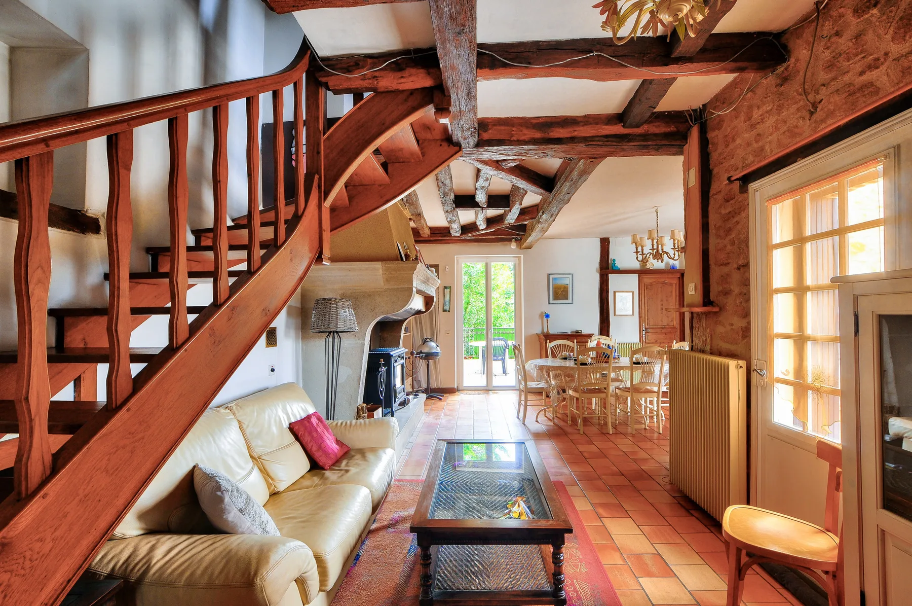 Sala de estar y comedor con vigas de madera vistas y una escalera.