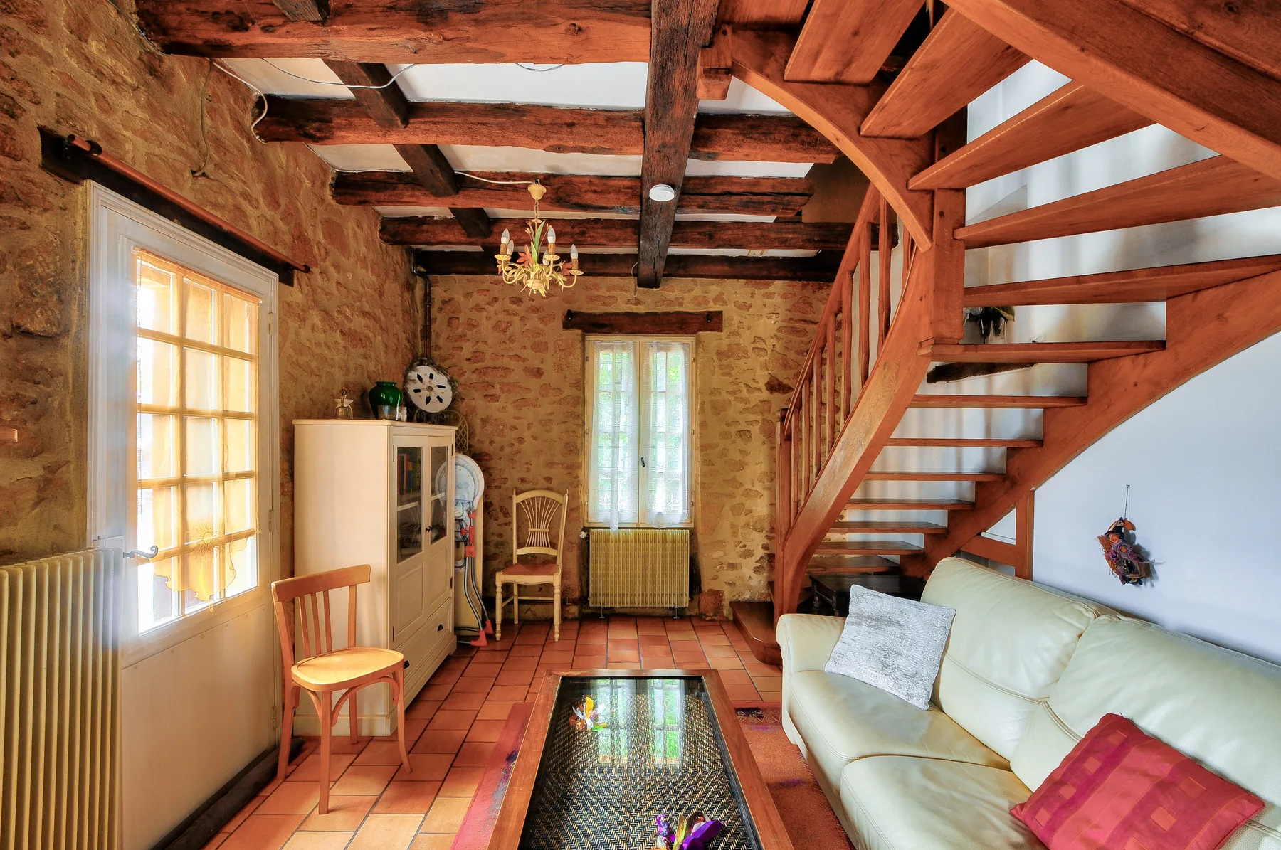 Una sala de estar de piedra con vigas de madera expuestas y una escalera.