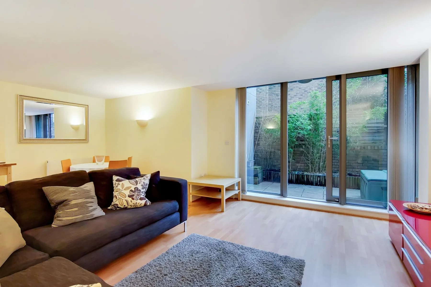 A living room with seating beside large glass doors opening onto greenery.