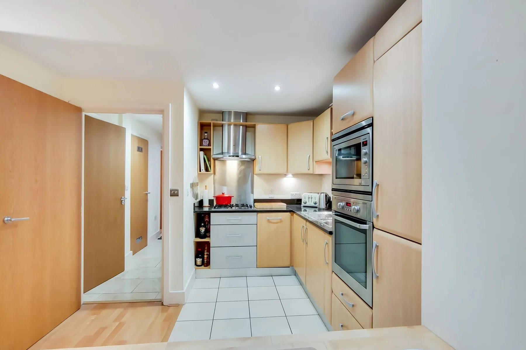 A kitchen with light wood cabinets and built-in appliances.