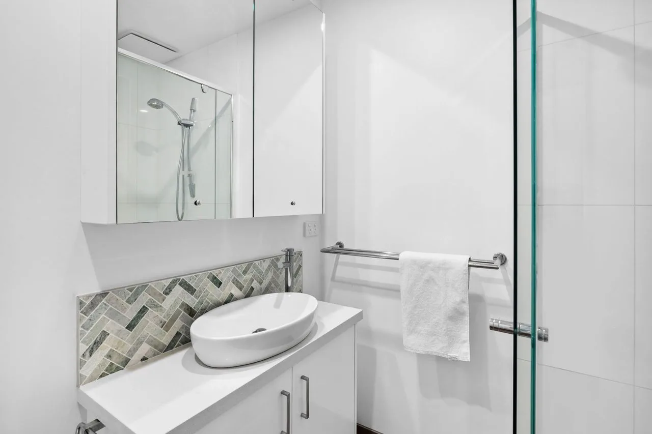 Un baño luminoso con lavabo sobre encimera y ducha de vidrio.