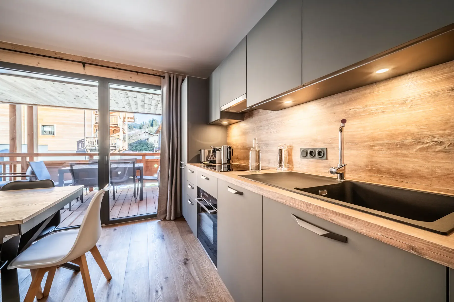 A kitchen with a table and chairs and a balcony.