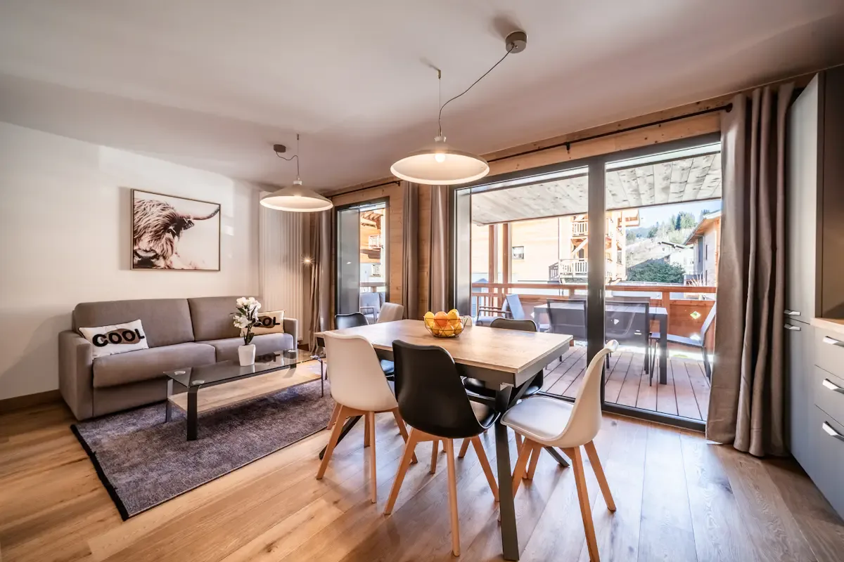 A bright living and dining area with a table beside large glass doors.