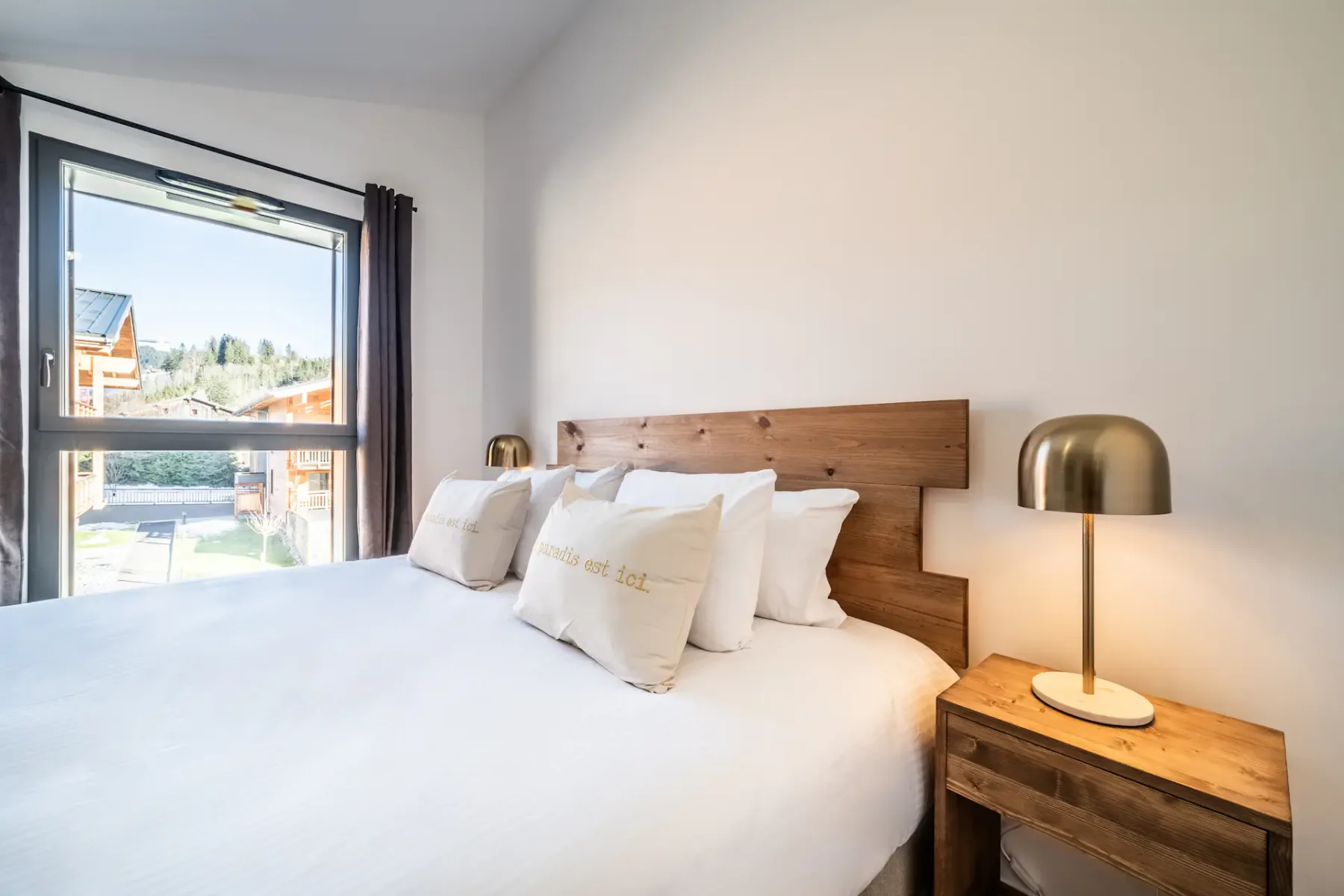 A bedroom with a bed, wooden headboard, and bedside table.