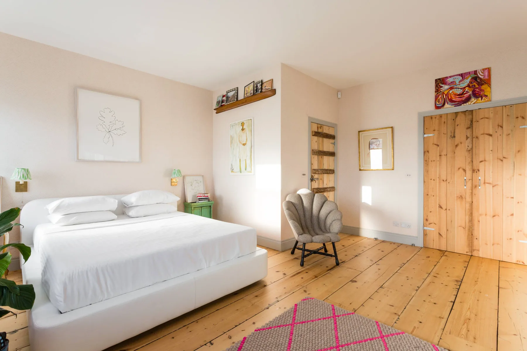 Dormitorio luminoso con una cama, una silla y suelo de madera.