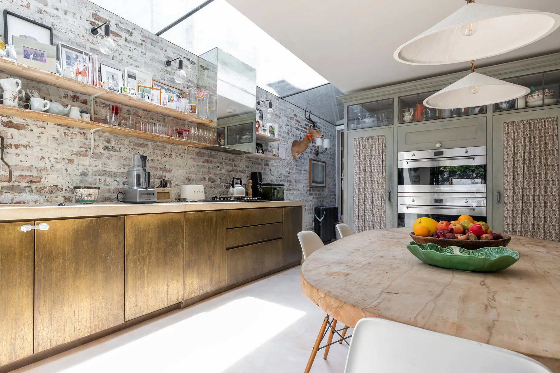 Una cocina con gabinetes de madera, estantes abiertos y una mesa redonda.