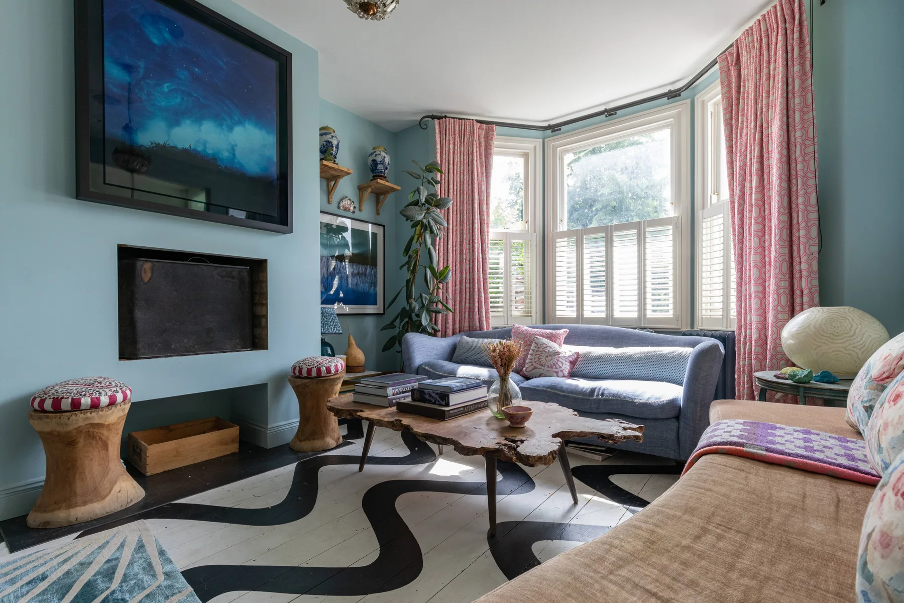 Una sala luminosa con asientos alrededor de una mesa de centro junto a grandes ventanas.