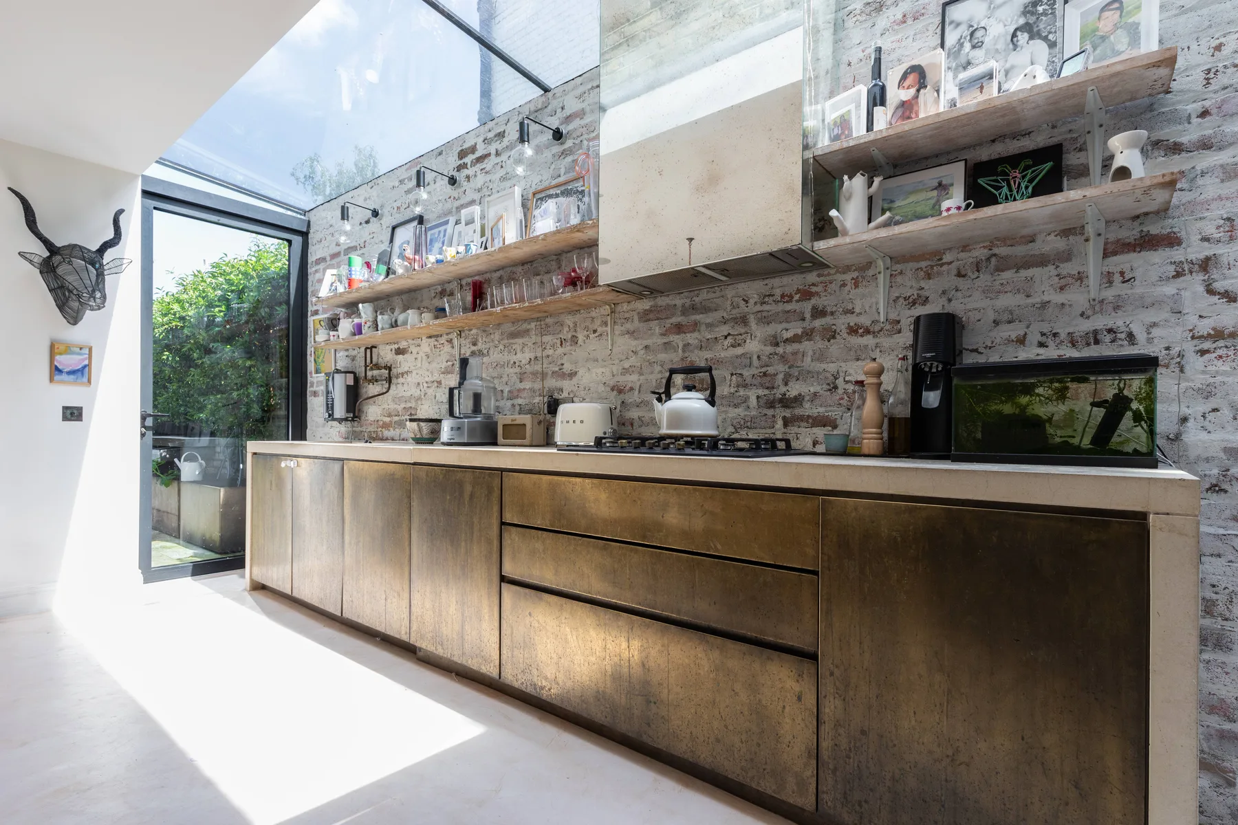 A bright kitchen with a long counter, open shelves, and a skylight.