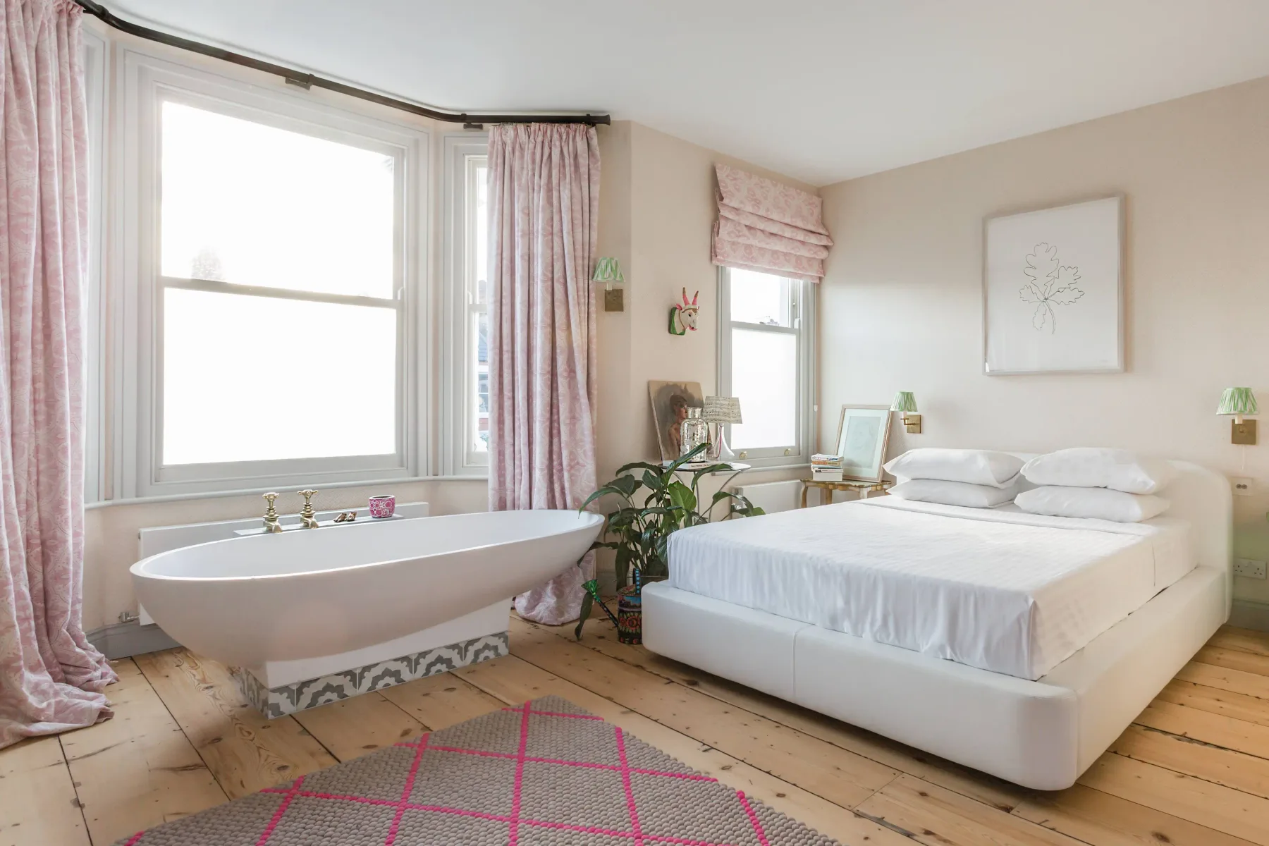 Un dormitorio con una cama blanca junto a una bañera exenta.