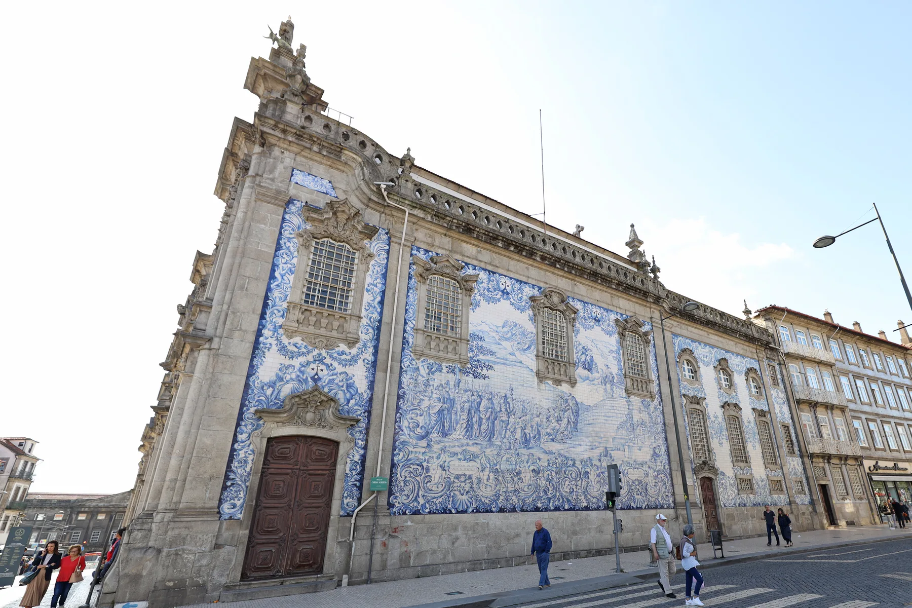 Fachada de una iglesia histórica cubierta de azulejos azules y blancos junto a una calle.
