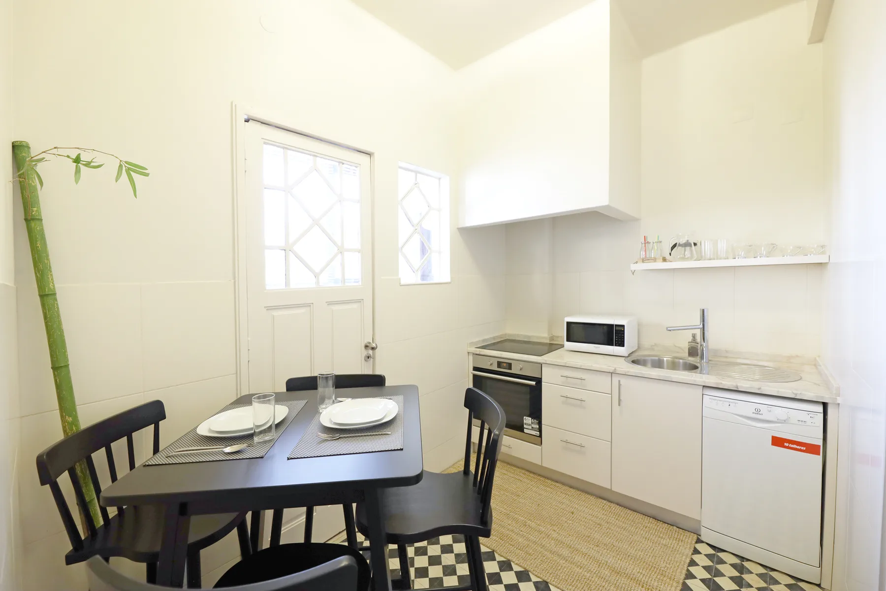 Comedor junto a una cocina compacta, con una mesa y electrodomésticos sobre la encimera.