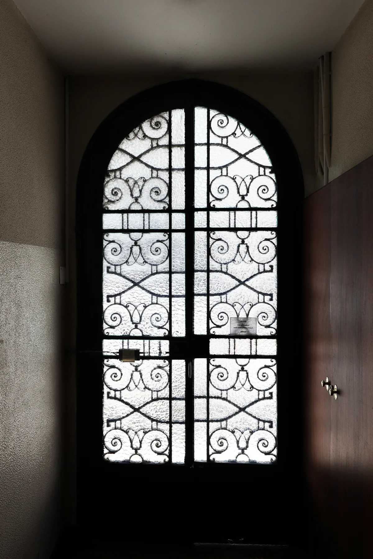 Un recibidor oscuro con una puerta arqueada de vidrio ornamentado.