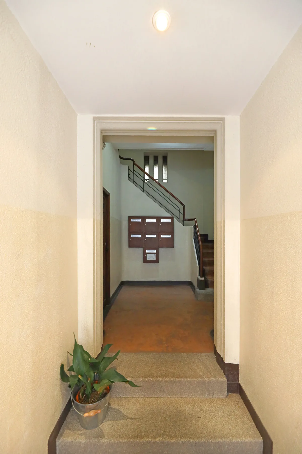 Un vestíbulo de entrada se abre a una escalera y a buzones en la pared.