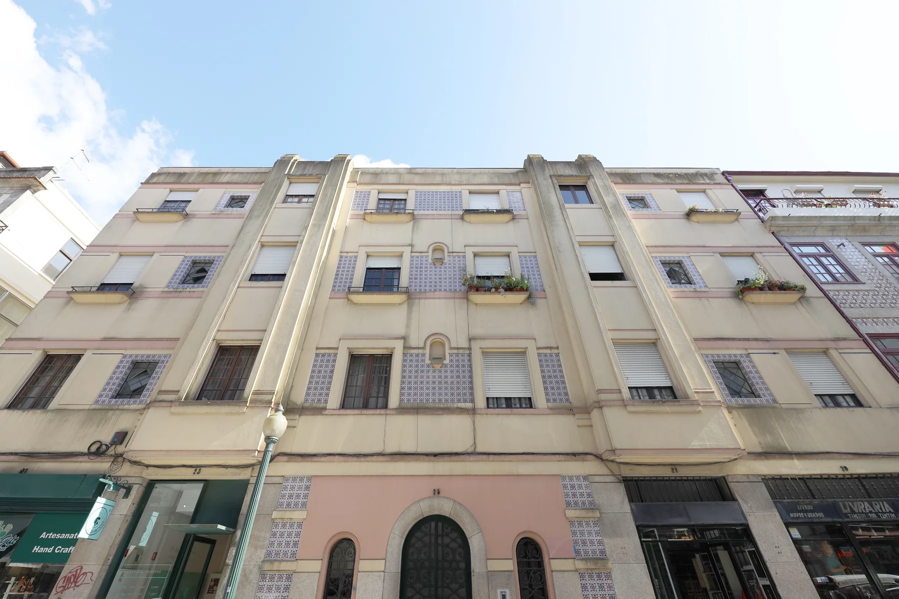 Vista desde abajo de la fachada de un edificio de varias plantas con balcones y ventanas.