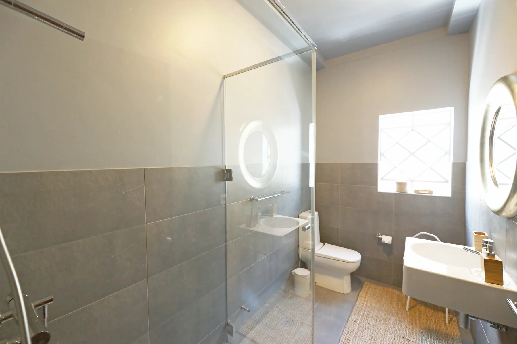 Un baño con ducha de vidrio, inodoro y lavabo suspendido.