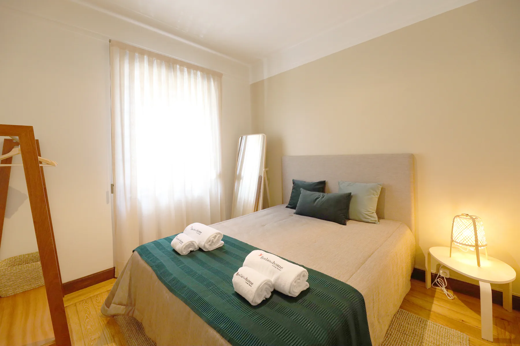 Dormitorio con una cama, toallas dobladas y una ventana luminosa.