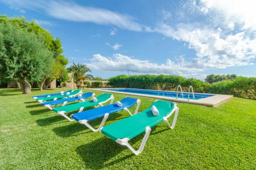 Zona de piscina y jardín con tumbonas dispuestas sobre el césped.