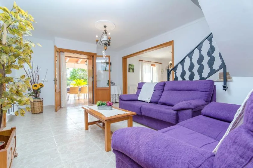 Una sala de estar con asientos morados y una mesa de centro de madera.