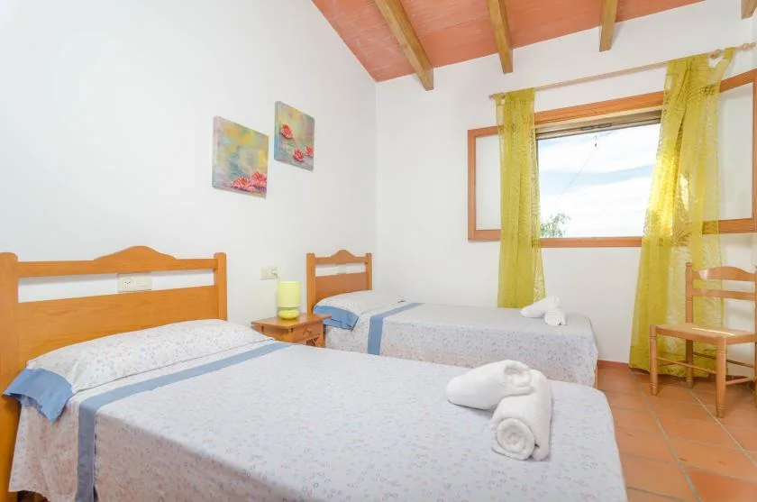 Un dormitorio con varias camas y una ventana enmarcada por cortinas amarillas.