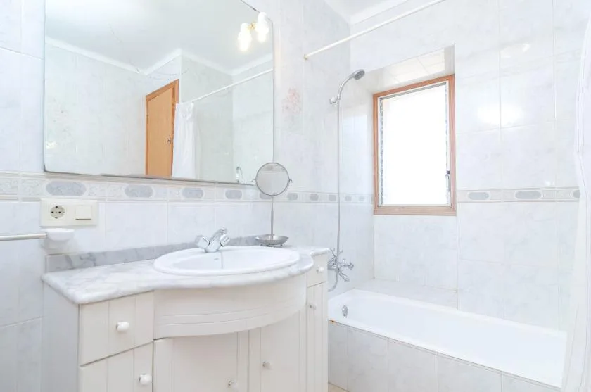 Baño luminoso con lavabo, espejo y bañera.
