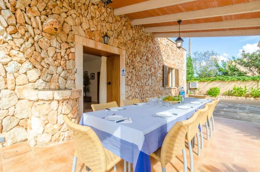 Un comedor exterior cubierto con una mesa larga junto a una pared de piedra.