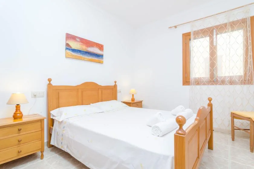 Un dormitorio luminoso con una cama de madera y una ventana con cortinas estampadas.