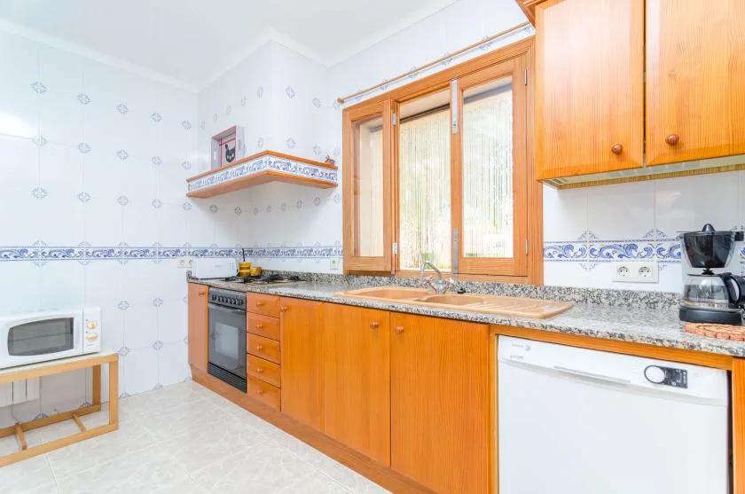 Una cocina luminosa con armarios de madera, una encimera y una ventana grande.