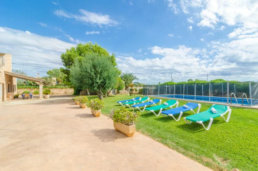 Una zona de piscina al aire libre con tumbonas sobre el césped.