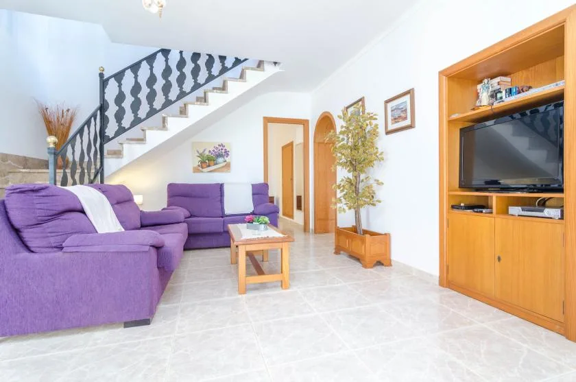 Una sala de estar con asientos morados, una mesa de centro y una escalera.