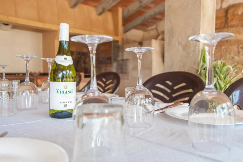 Una mesa está preparada con copas de vino, platos y una botella de vino.