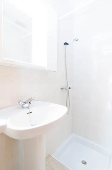 Un baño luminoso con lavabo de pedestal y zona de ducha.