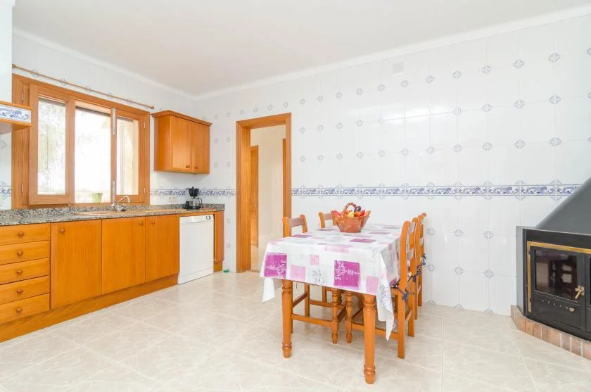 Cocina y comedor con azulejos, armarios de madera y una mesa.