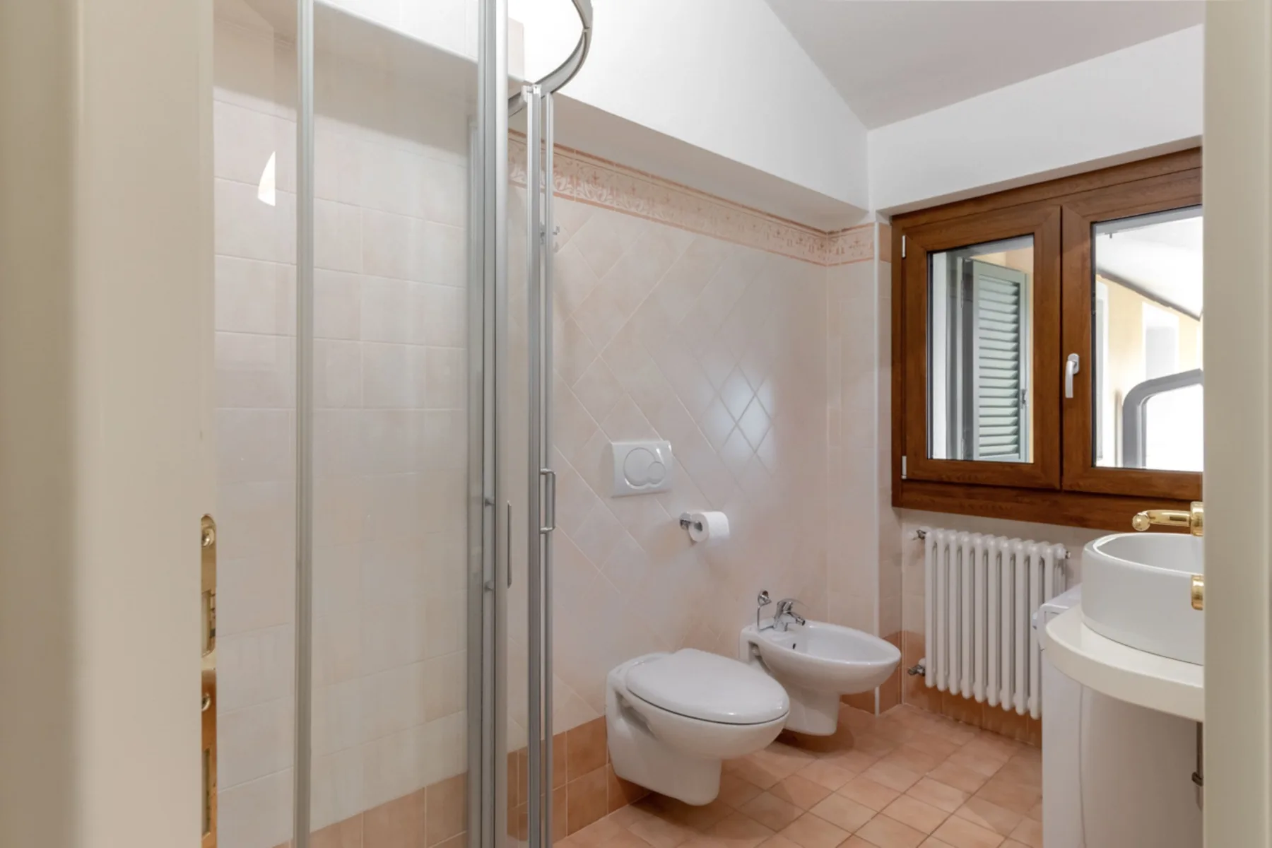 Un baño alicatado con ducha de vidrio, inodoro, bidé y lavabo.