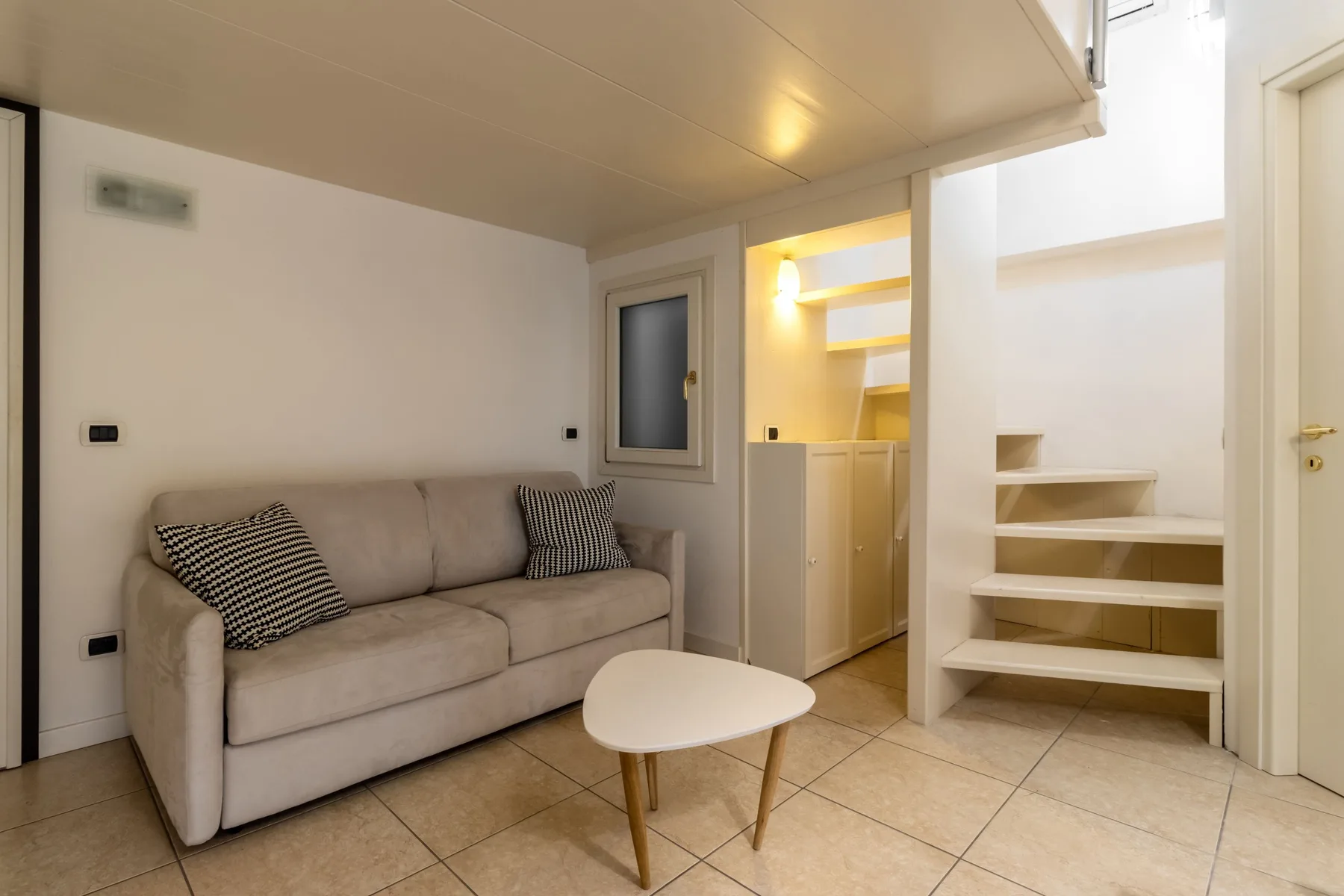 Una pequeña sala de estar con sofá, mesa de centro y estanterías empotradas.