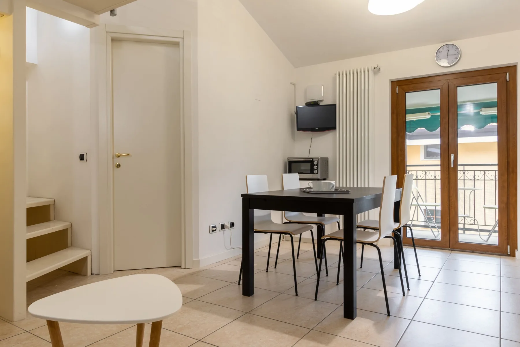 Un comedor luminoso con una mesa y puertas de cristal que dan a un balcón.