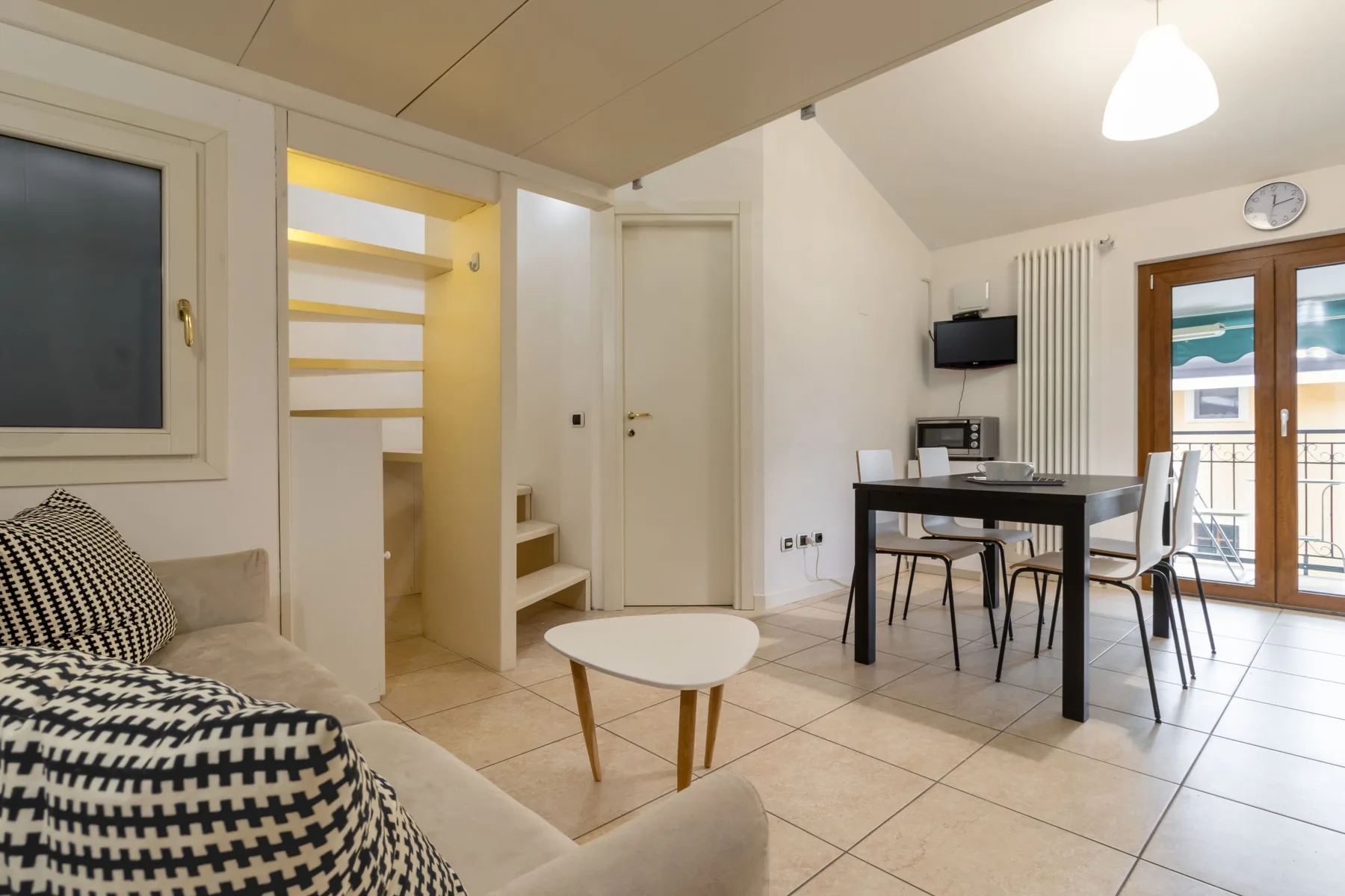 Una sala de estar y comedor con asientos, una mesa y puertas que dan a un balcón.